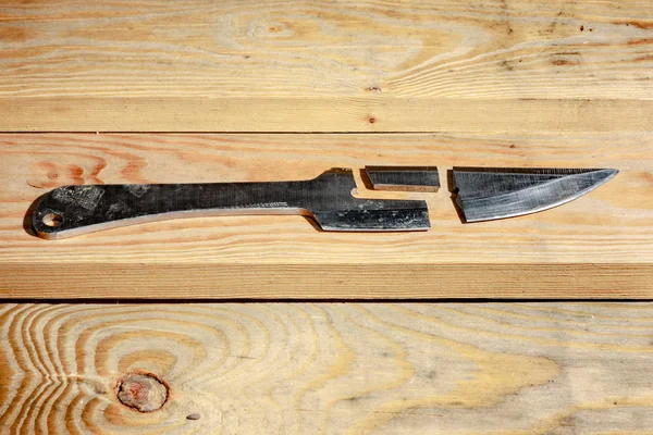 Broken throwing knife on a wooden background