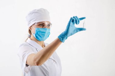Beyaz önlüklü bir doktor ilaçlara bakar.