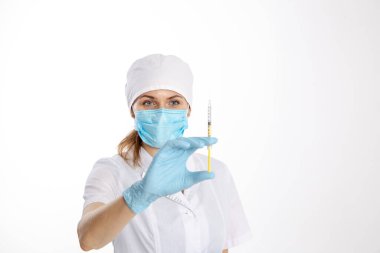 Beyaz önlüklü doktor elinde şırınga tutuyor.