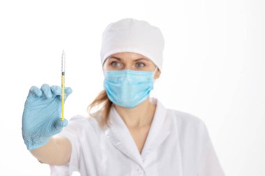 Beyaz önlüklü doktor elinde şırınga tutuyor.