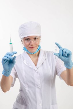 Beyaz önlüklü doktor elinde şırınga tutuyor.