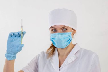 Beyaz önlüklü doktor elinde şırınga tutuyor.