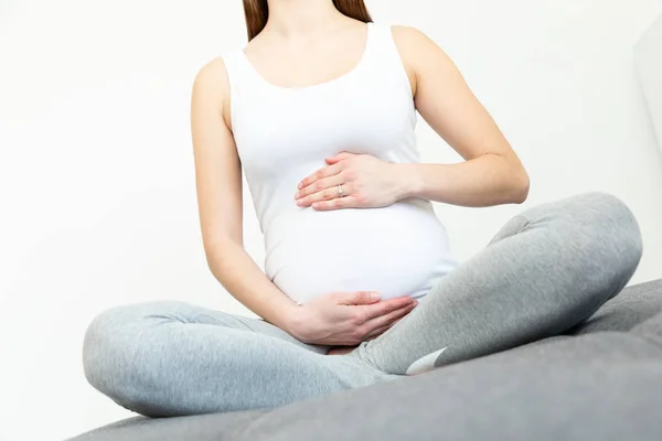 Mladá těhotná žena drží své břicho sedí na pohovce - Pohlaví — Stock fotografie