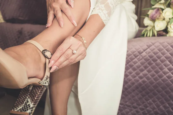 Noiva coloca em sapatos de casamento em seus pés macios — Fotografia de Stock