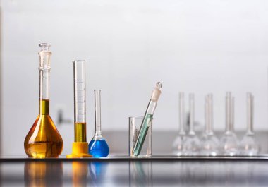 Gerçek bir laboratuvarda renkli reaktör çözeltileri olan bir kavanoz ve matara seti. Metin yerleştirme için büyük boş boşluk.