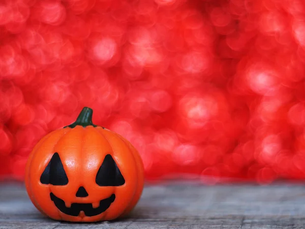 Dynia Halloween na drewnianym stole nad czerwonym bokeh zadumany — Zdjęcie stockowe