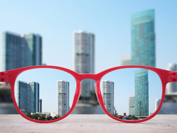 Edifícios altos perto do rio focados em lentes de óculos vermelhos — Fotografia de Stock