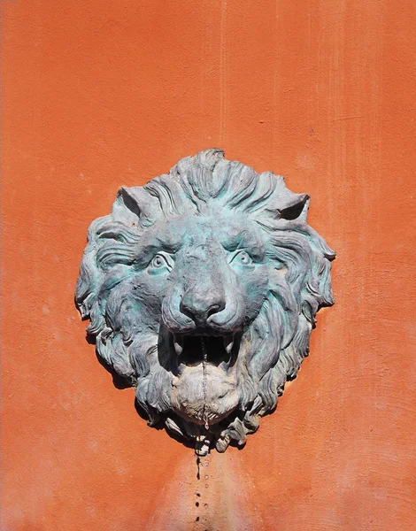 Lion head fountain on orange concrete wall — Stock Photo, Image