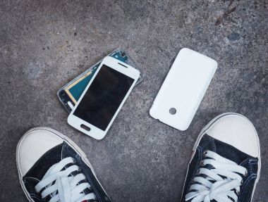 Kırık akıllı telefon sahibinin spor ayakkabı sho arasında beton zemin