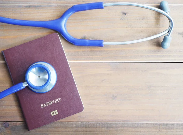 Stetoscopio e passaporto su fondo legno — Foto Stock