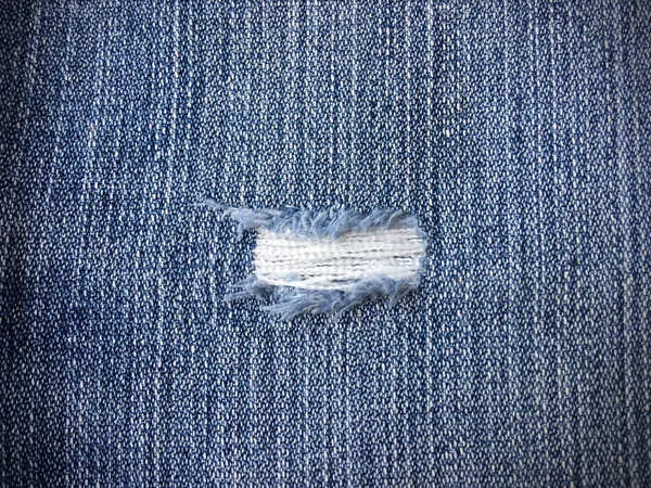 Texture di jeans blu con un foro — Foto Stock