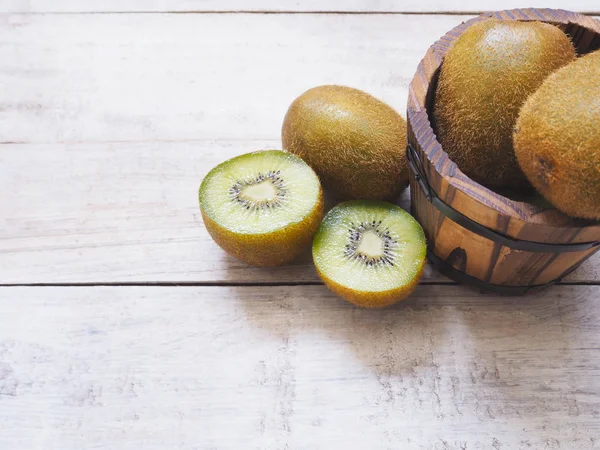 Beyaz ahşap zemin üzerinde kivi meyve ve varil kova. 