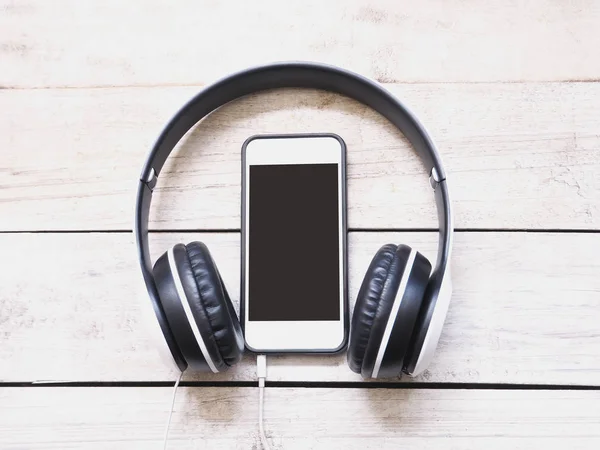 Kulaklık ve Beyaz ahşap arka plan üstünde hareket eden telefon.