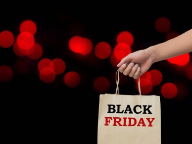 Arka plan üzerinde kırmızı bokeh üzerinde kahverengi alışveriş çantası tutan el