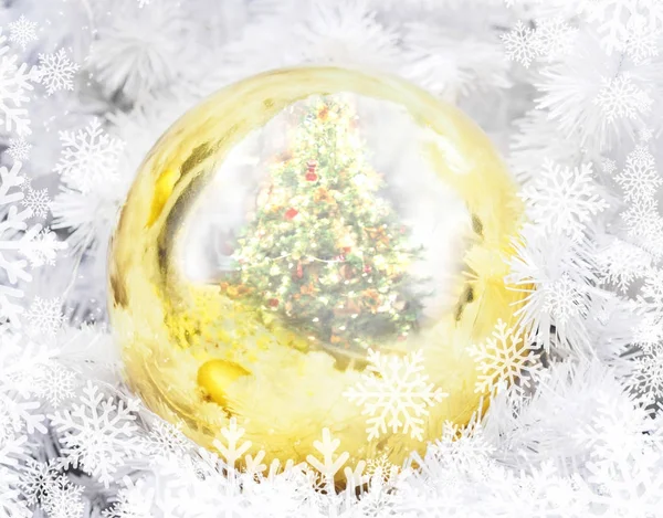 Goldene Weihnachtskugel mit Tannenspiegelung und Schneeflocken — Stockfoto