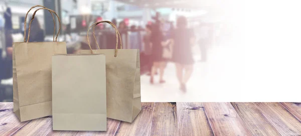 Bruin boodschappentassen op houten tafel over wazig verkoop winkel — Stockfoto