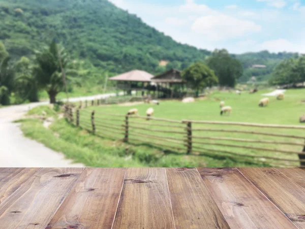 Wood table top over blurry flock of sheep grazing at farm — Stock Photo, Image