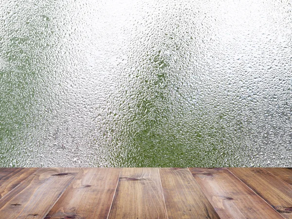 Древесный стол поверх капель воды на прозрачном стекле — стоковое фото