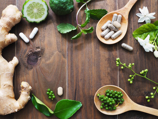 травяные таблетки в деревянной ложке и травах
