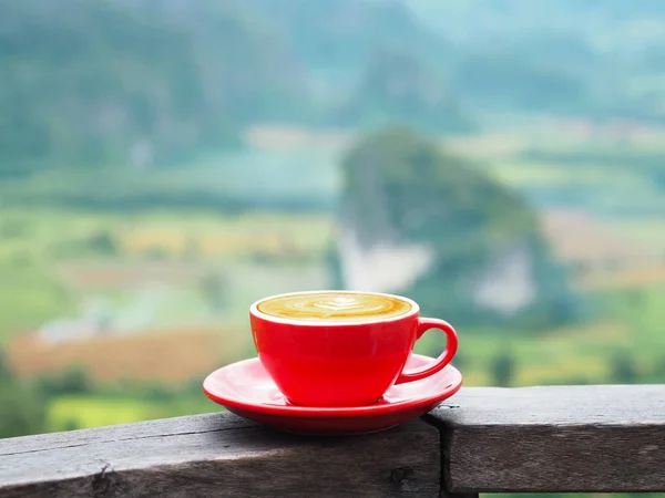 Närbild röd kopp latte kaffe över suddig berg bakgrund — Stockfoto
