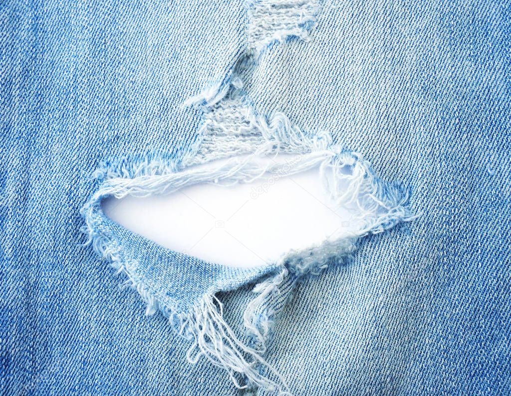 ripped torn pattern of light blue denim jeans on white backgroun