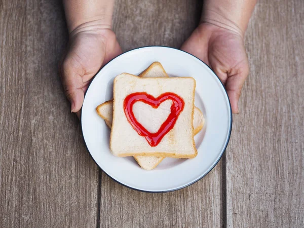 Mulher gorda mão segurando prato de pão com geléia de frutas vermelhas coração s — Fotografia de Stock