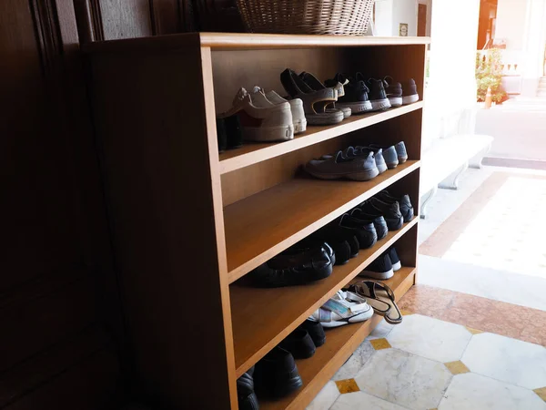 Wooden shoe cabinet with shoes at entrance door to the house.
