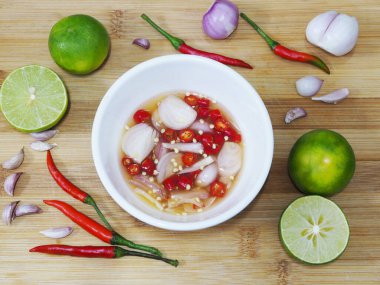 Beyaz kâse balık sosu ve ahşap kesim tahtası arka planındaki bitki malzemelerinin üst görüntüsü..