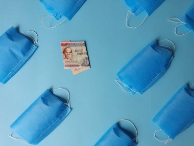 Mavi arka planda 50 dolarlık Jamaika banknotları ve maskeler.