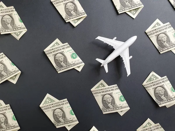 Amerikan 1 dolarlık banknotlar ve siyah arka planda beyaz plastik bir uçak figürü.