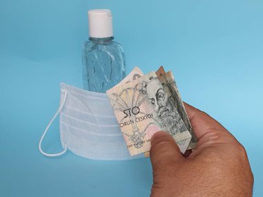 Maske ve bir şişe jöle için para ödeyen bir adamın eli.