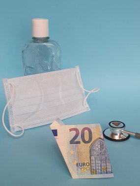 Avrupa banknotu 20 avro, maske, jel alkollü şişe ve mavi arka planda steteskop