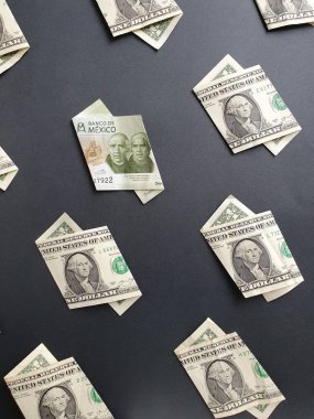 Bir dolarlık Amerikan banknotları ve siyah arka planda 200 pezoluk Meksika banknotları.