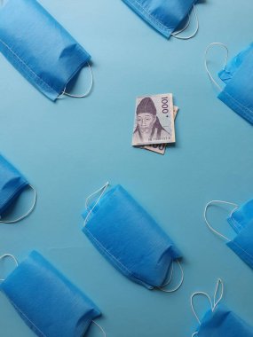 Güney Kore banknotu 1000 won ve mavi arka planda maskeler.