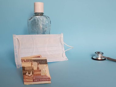 2000 riyal, maske, jel alkollü şişe ve mavi arka planda steteskop İran banknotları.