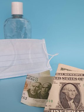 Amerikan ve Meksika banknotları, maske, jel alkollü şişe ve mavi arka plan
