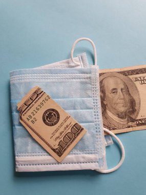 100 dolarlık bozuk Amerikan banknotu, maske ve mavi arka plan