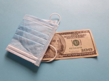 Maske, 100 dolarlık Amerikan banknotu ve mavi arka plan