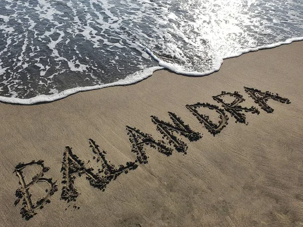 Balandra el yazısı plaj kumu, arkaplan ve doku ile yazılmış