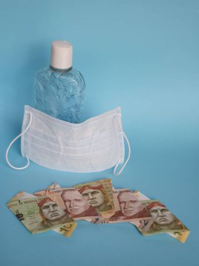 Peru banknotları, yüz maskesi, jel alkollü şişe ve mavi arka plan