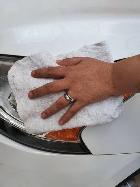 hand of a woman cleaning the headlight of a vehicle