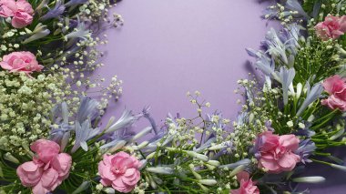 Mor arkaplanda çiçek demeti içinde mor agapanthus çiçeği ve pembe karanfil çiçekleri.