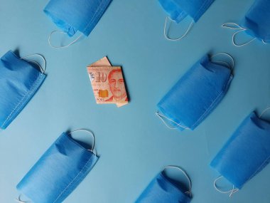 Mavi arka planda 10 dolarlık Singapur banknotları ve maskeler