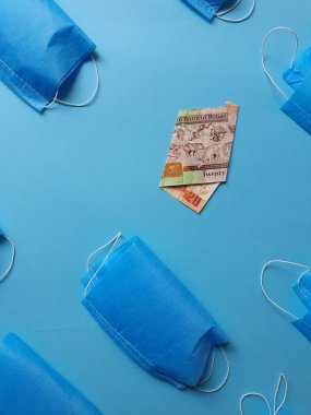 Maske ve 20 dolarlık banknot mavi arka planda.