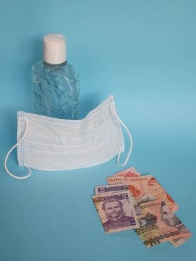 Honduras banknotları, yüz maskesi, jel alkollü şişe ve mavi arka plan