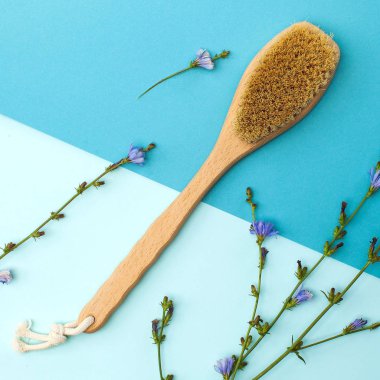 anti-selülit masaj fırçası küçük mor çiçekleri olan renkli bir arkaplanda yakın plan