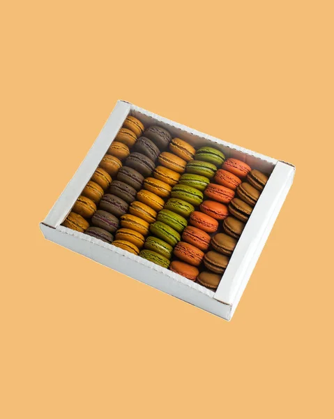 Wielokolorowe makaroniki makaronowe w pudełku tekturowym na kolorowym tle — Zdjęcie stockowe