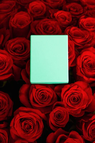 turquoise gift box for jewelry on a bouquet of red roses flatlay
