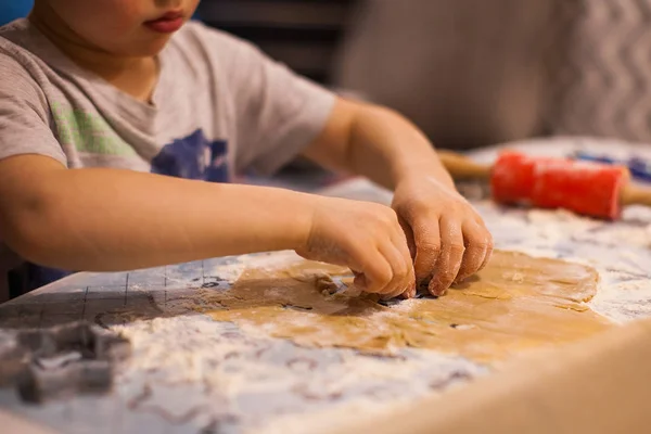 Un niño corta una galleta de jengibre con un cortador de galletas en Nochevieja —  Fotos de Stock
