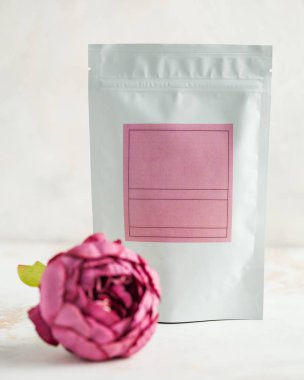 Çay, kahve için ambalaj, pembe etiketli katı maddeler, ön planda pembe şakayık çiçeği